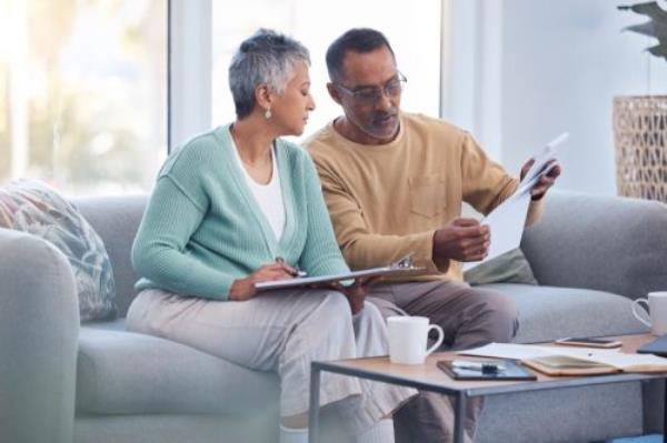 Couple planning a vacation trip sits on the floor looking at a map and a tablet