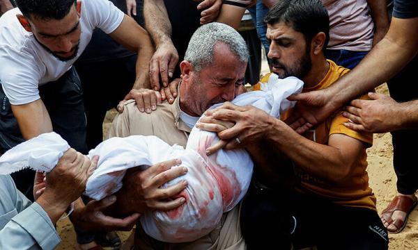  A mourner reacts while burying the body of a Palestinian child of al-Agha family, who was killed in Israeli strikes, in Khan Younis in the southern Gaza Strip on October 11, 2023. — Reuters 