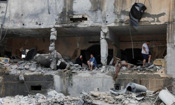 Palestinians sit and walk among rubbles of a damaged residential building, in the aftermath of Israeli strikes, in Gaza City, October 10, 2023. — Reuters