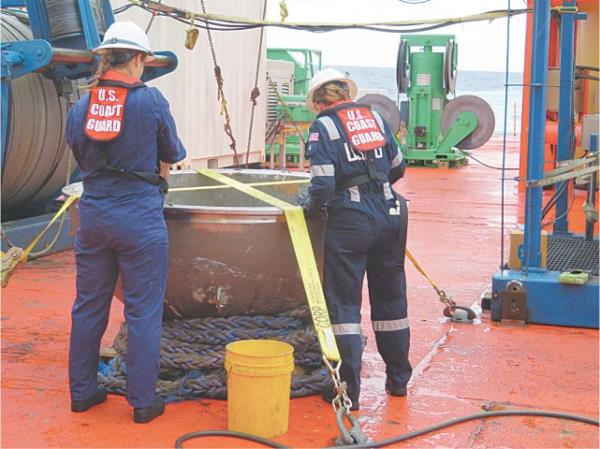 MARINE engineers from the US coast guard examine the titanium end cap from Titan in the North Atlantic Ocean.—AFP